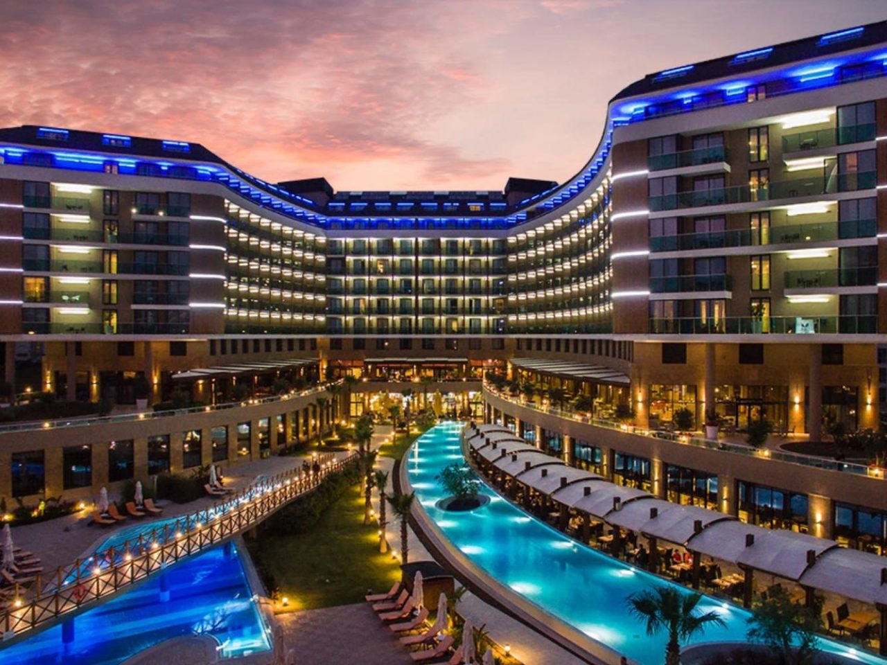 Aska Lara Resort beleuchtetes Hotel mit Poollandschaft bei Abenddämmerung