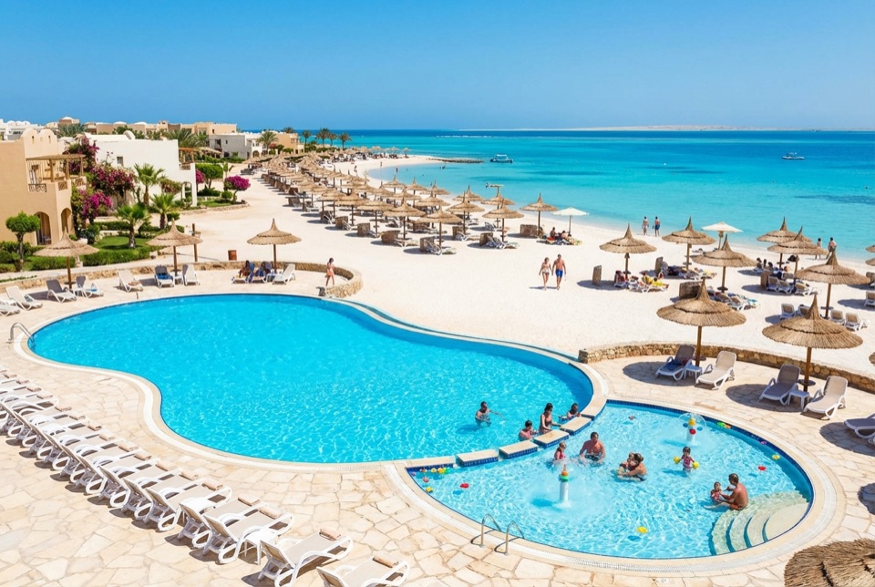 Poolanlage eines Familienhotels in Hurghada mit flachem Kinderbecken, Sonnenschirmen und dem türkisfarbenen Roten Meer dahinter