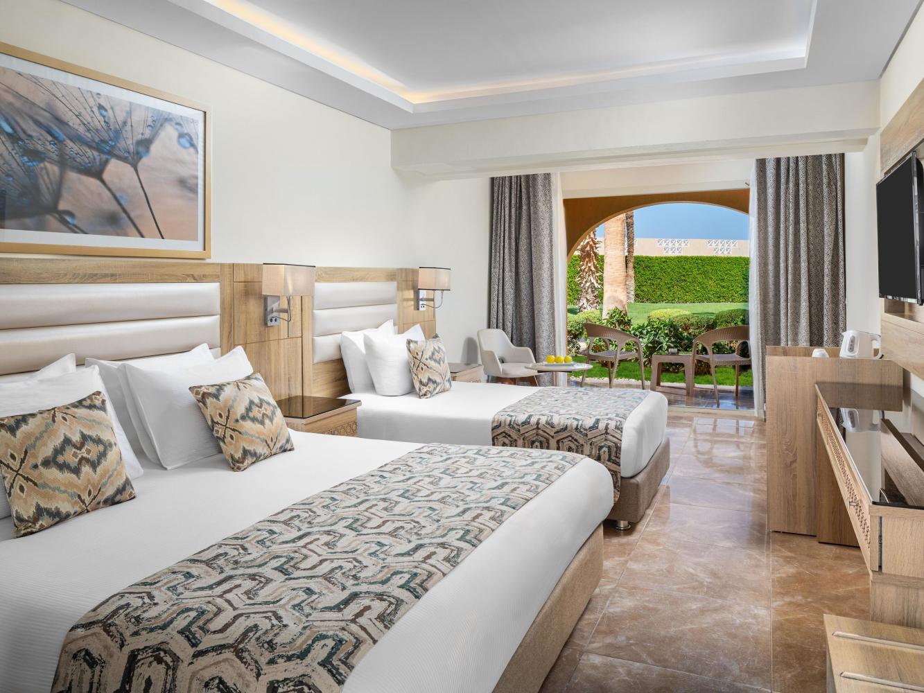 Familienzimmer im Beach Albatros Resort in Hurghada mit zwei Doppelbetten, Sitzecke und Terrassentür zum Garten