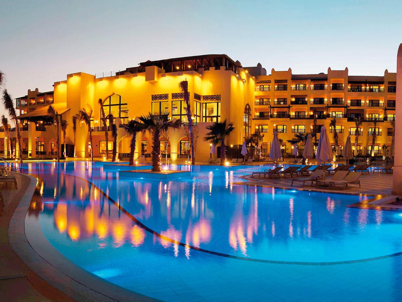 Steigenberger Aqua Magic in Hurghada in der Abenddämmerung, beleuchtetes Hotelgebäude hinter der großen Poollandschaft