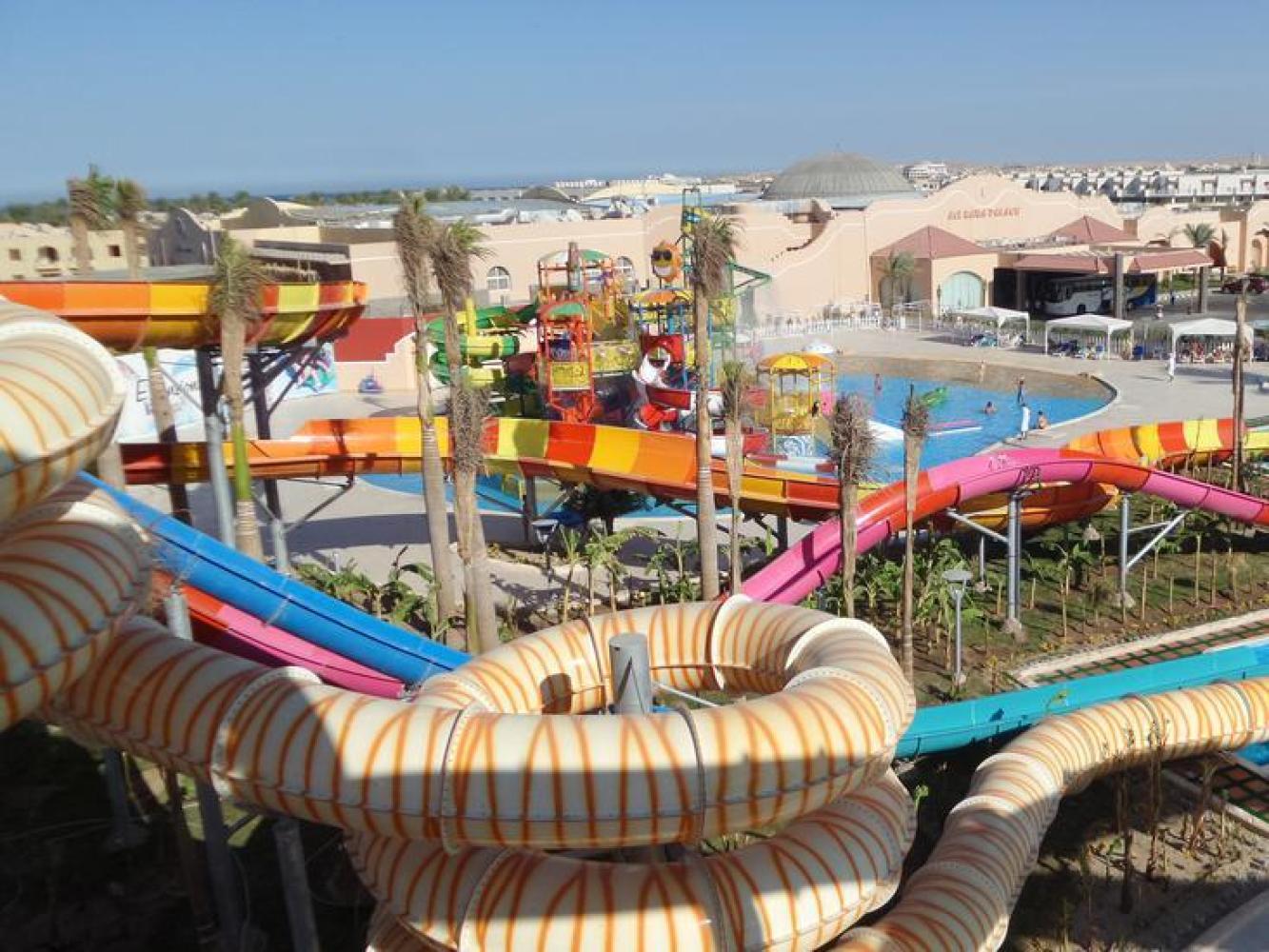 Aquapark mit bunten Rutschen und flachem Kinderbecken, dahinter die Hotelanlage